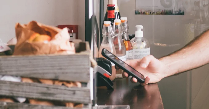 hand holding phone behind a restaurant check out counter