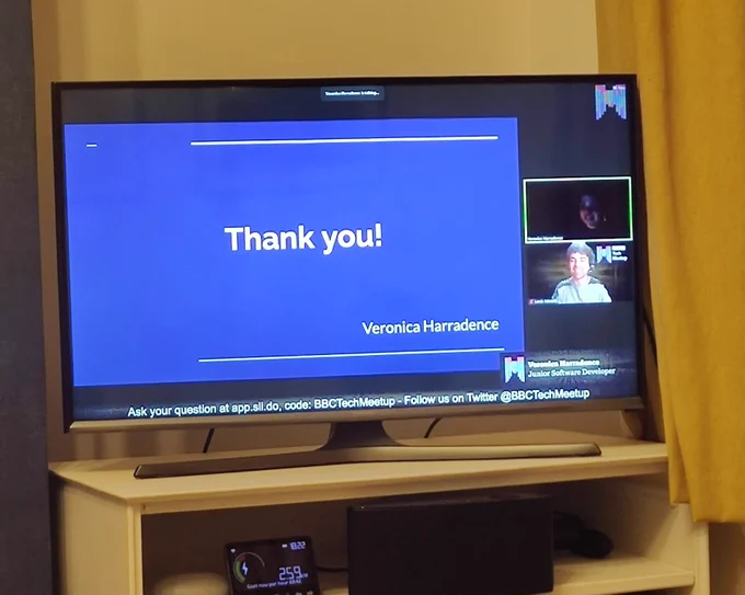 A TV showing a "Thank you" slide and the person giving the presentation.