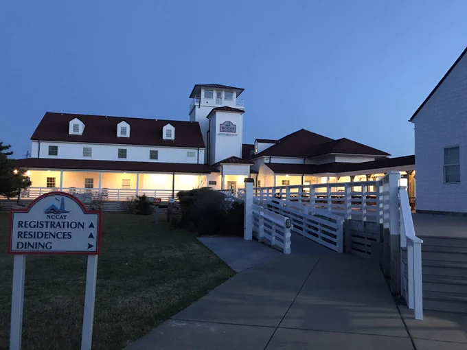 A twilight photo of NCCAT in Ocracoke, NC. A white building with a red tin roof.