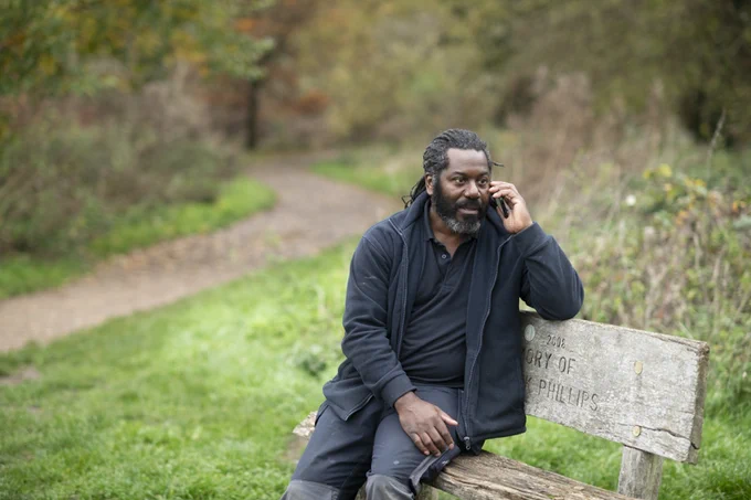 Man sitting on the bench in the park, talking on the phone to someone 
