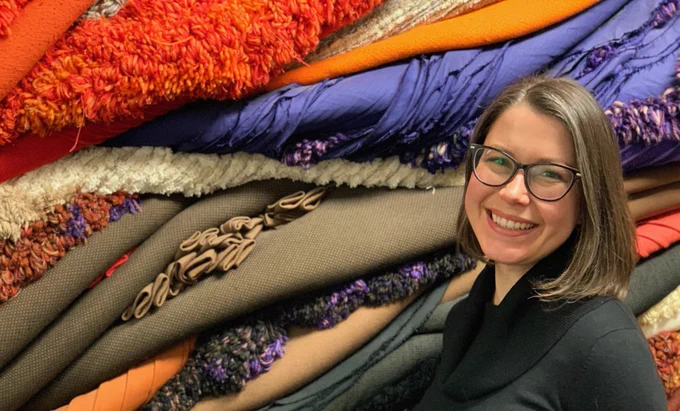 Reuther Library Director Aliqae Geraci portrait standing in front of abstract textile art. 