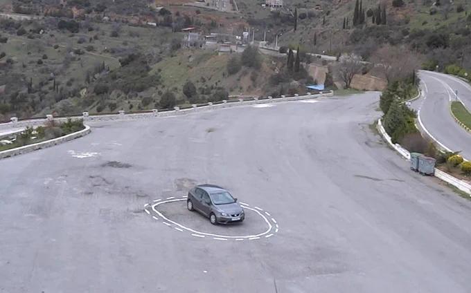 Photo: an empty asphalt area. In center frame, a car is trapped inside a salt circle that resembles "no lane change" markings.