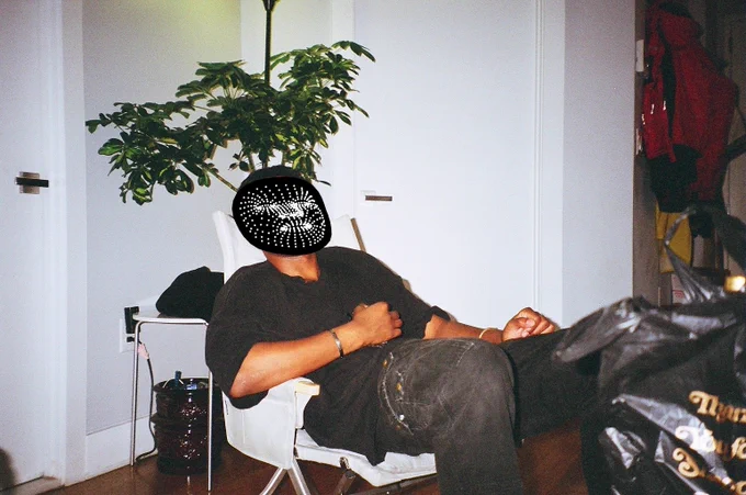bomani oseni mclendon sits in a chair face overlaid with black circle and white dots tracking facial features