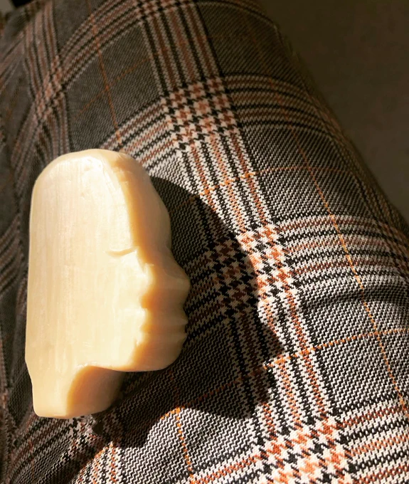a soap bar carved into a side profile portrait on a plaid fabric surface
