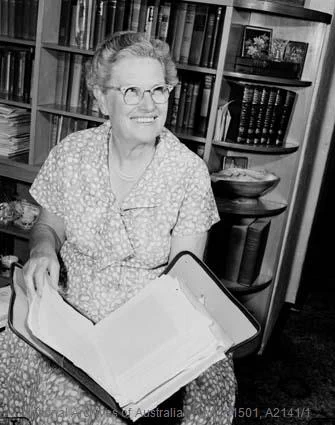 Black and white photo of Ruby Hutchinson with a big smile, sitting down reading a book