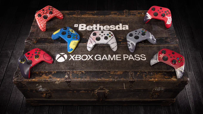 7 Xbox controllers sit on top of a wooden chest. The Bethesda and Xbox Game Pass logos are written on the top of the chest as well.