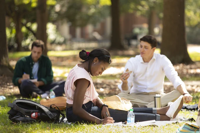 Second year law student Tatiana Mosbey, middle, writes down her answers to the trivia questions as she enjoys lunch and a game of trivia with fellow law students at the Law School Luncheon on the Grass in front of the Law Library on North Campus.