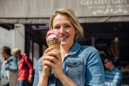 A smiling woman holding an ice cream cone in Brighton. 