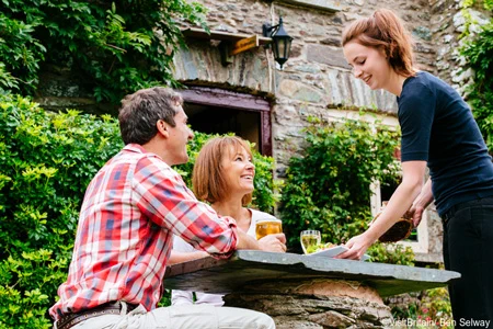 A couple being served by a waitress at an outdoor pub table in Exmoor. ©VisitBritain/ Ben Selway