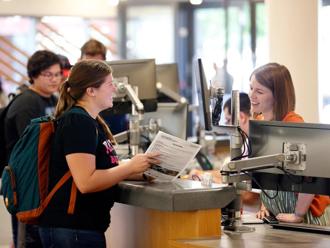 Librarian helps student at the desk
