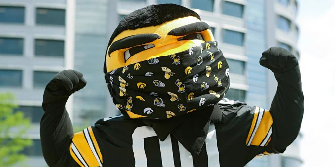 Herky wearing a face mask in front of the UI Stead Family Children's Hospital