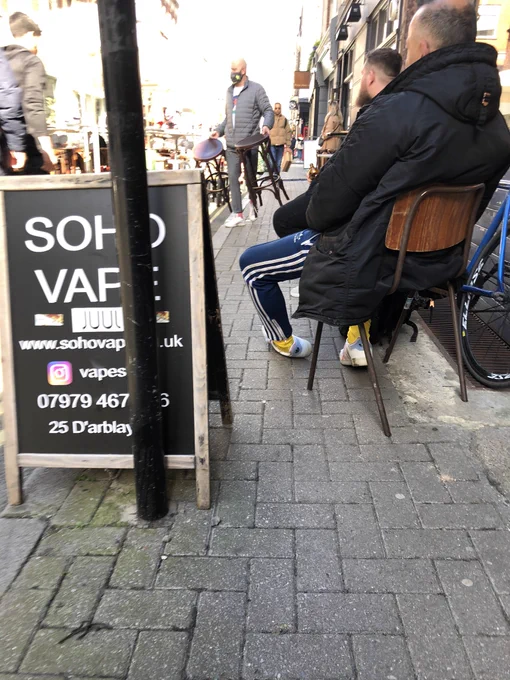 A pavement which is fully obstructed by a combination of a-boards and chairs.