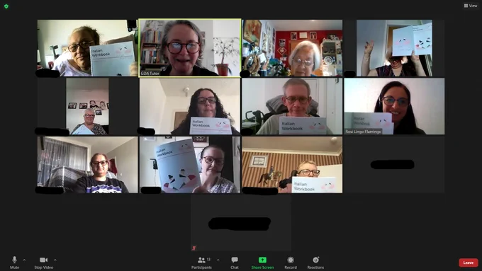 Members gather on zoom to learn italian - participants hold up their language books for the camera. 