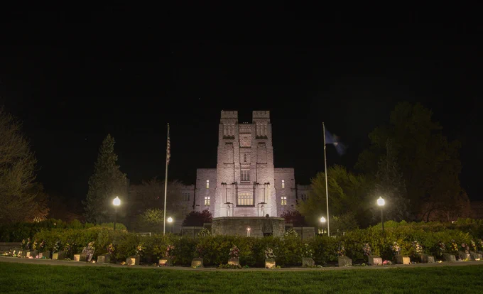 A nighttime photo of the April 16 memorial at Virginia Tech, with Burruss in the background. 
