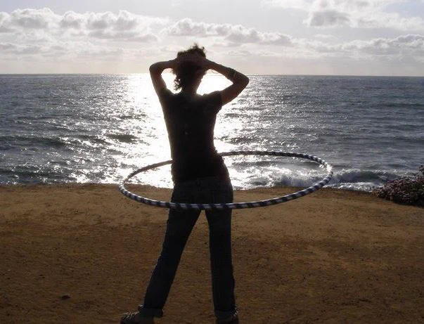 woman silhouette hula hooping on beach st sunset