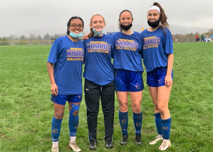 Senior members of the girls soccer team posing together after a game. 