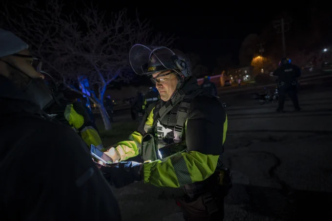 Police photograph the face and identification of a member of the press covering the protest.