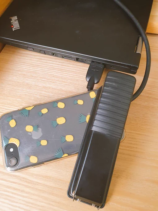 Phone and stapler holding a HDMI cable in place on a black laptop