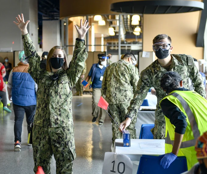U.S. Navy Ensign Christina Erickson, a Quincy, California, native and registered nurse assigned to Navy Medicine Readiness and Training Command, Camp Pendleton, California, signals that a vaccination station is ready to help the next community member at the Community Vaccination Center in St. Louis, Missouri, April 14, 2021.