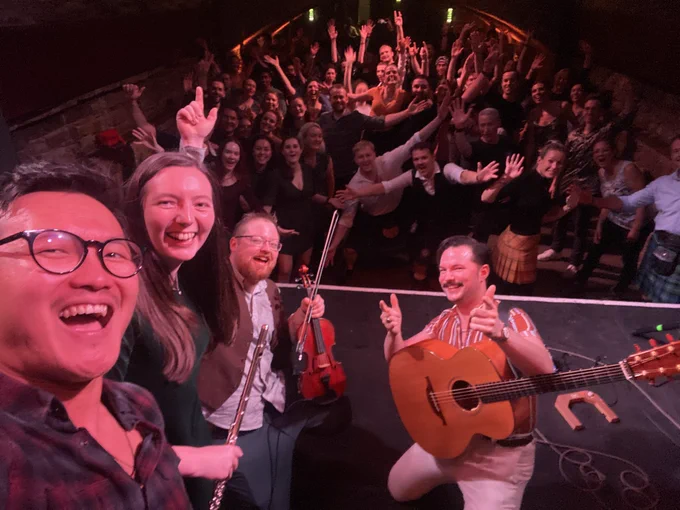 The band taking a selfie with a bunch of legends at a Ceilidh
