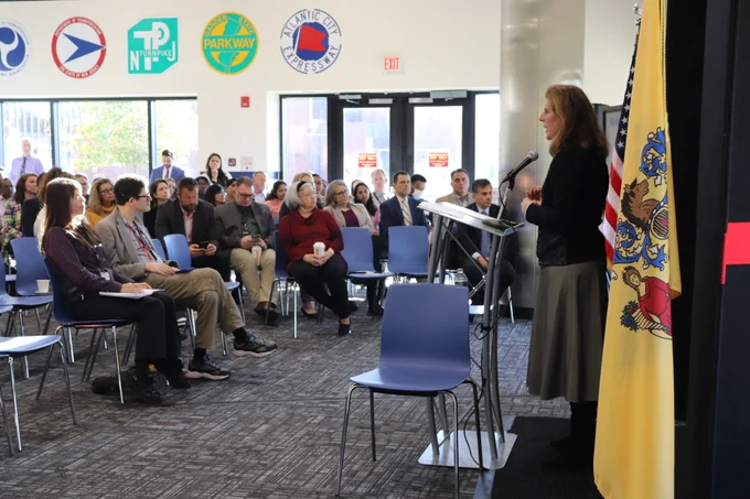 Stephanie Hoopes stands at a podium at the NJ Department of Transportation and addresses a room full of seated professionals