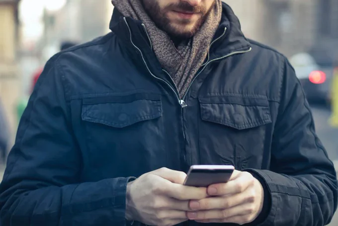 Person in a blue coat texts on their phone