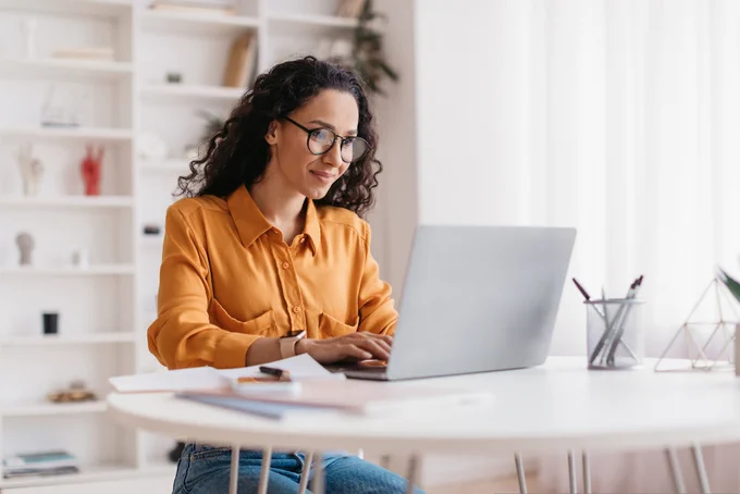 Woman of middle Eastern descent using Laptop Working Online Wearing glasses