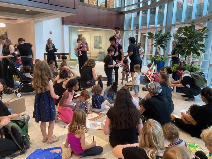 A group of parents and kids in a lobby making signs