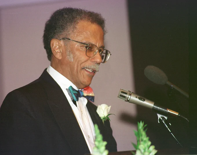 Warren Washington speaking into microphones.