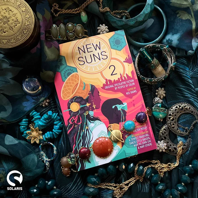  A paperback copy of NEW SUNS 2 edited by Nisi Shawl lies on teal fabric with a collection of gold and turquoise objects.