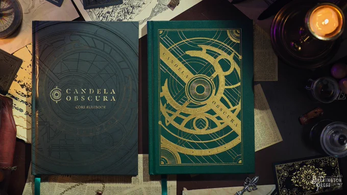 A photo of the standard and limited edition covers of the Candela Obscura Core Rulebook on a desk with notes and a candle.
