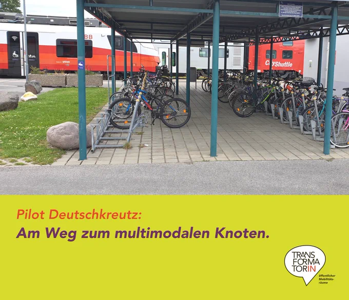 Bahnhof von Deutschkreutz mit Fahrradabstellplatz und wartenden Zügen im Hintergrund. 