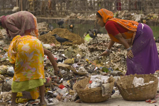 Some women gather items from a rubbish tip