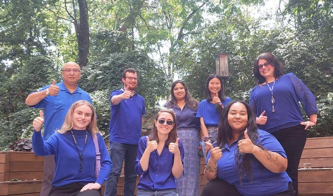 A group photo of Education Week workers with their thumbs up!