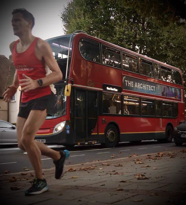 A runner from London Front Runners keeps pace alongside The Architect’s red bus, as it passes along the Well Hall Road.