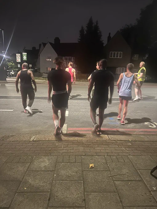 Runners from across London, including The Big Run, Black Trail Runners, Cambridge Harriers and runners who were on the street and asked to take part, are seen crossing the road to meet the bus that they will soon run alongside, as part of the performance of The Architect