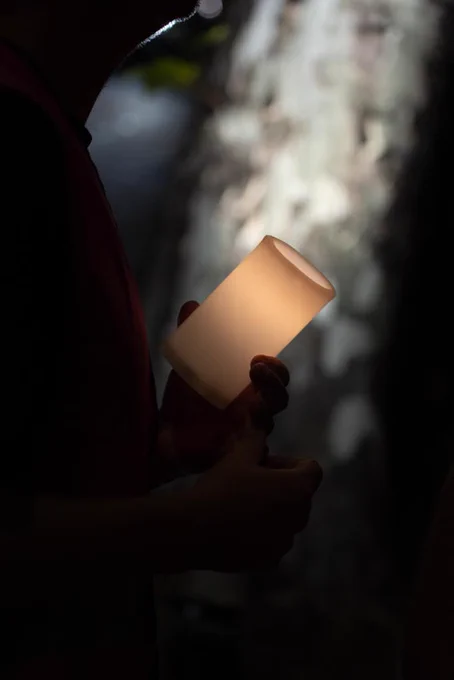 A candle brought by one of the runners to the Stephen Lawrence memorial plaque on Well Hall Road. It’s lit up and held by the runner against a background of nighttime.