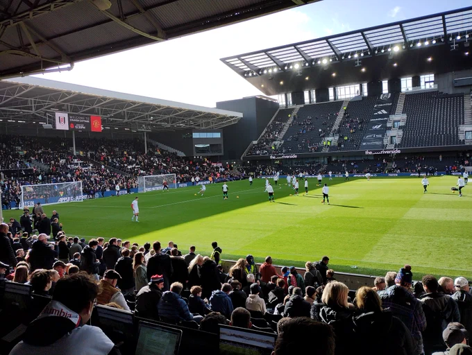 Image of the sunlit craven cottage pitch as players warm up before kickoff 