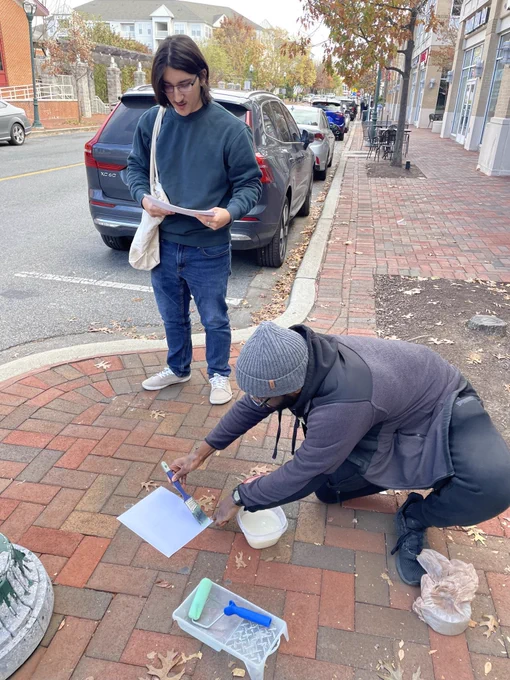 Two people setting up a poster to paste