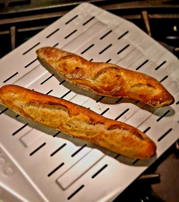 Two homemade baguettes on a pizza peel.