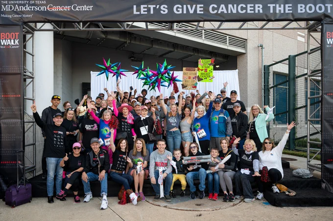 A group of people cheering, waving and holding signs at MD Anderson's Boot Walk to End Cancer