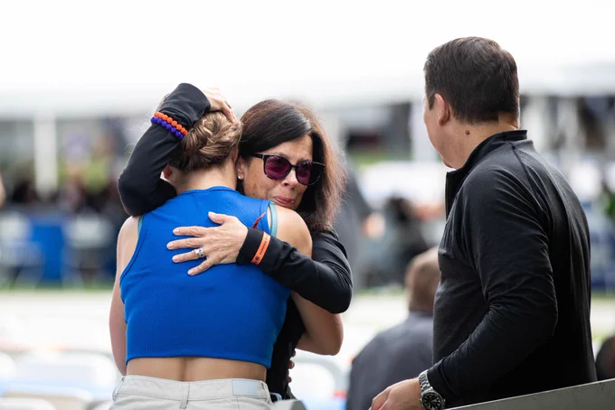 A mother embraces her daughter in a tight hug while holding back tears of joy.
