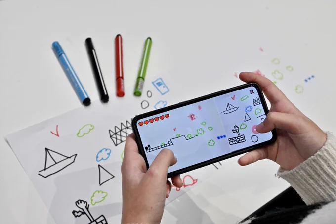 A child who, after photographing his drawing from the Draw Your Game Infinite application, plays his drawing transformed into a video game level.