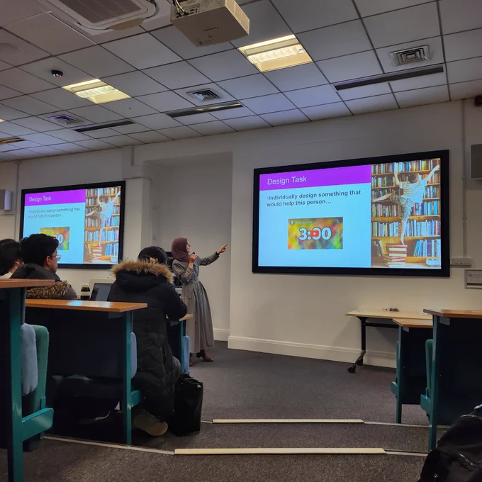 Dr Sarah Junaid standing in front of a slide setting out the first design task for our students.