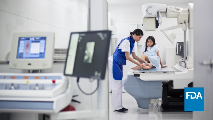 A technician helps a young girl get ready for an X-ray of her leg. 
