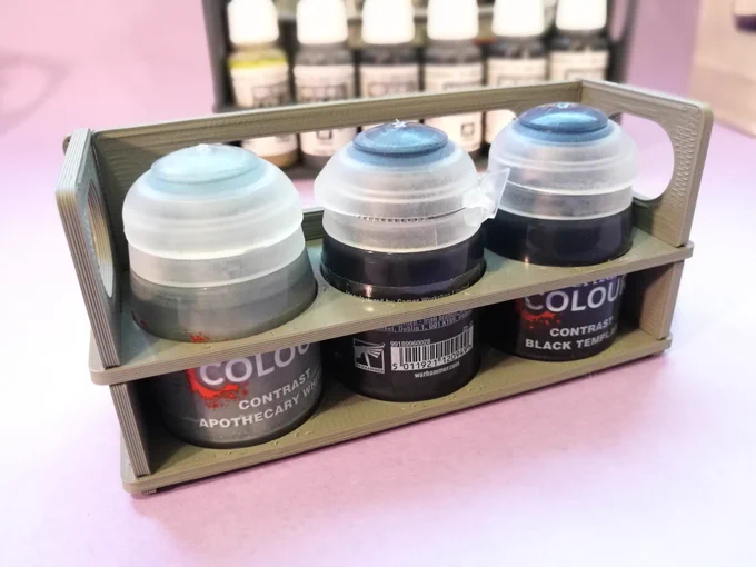 A 3d printed gray stand with three Citadel Color paint pots from the Contrast range: Apothecary White, Basilicanum Grey and Black Templar.