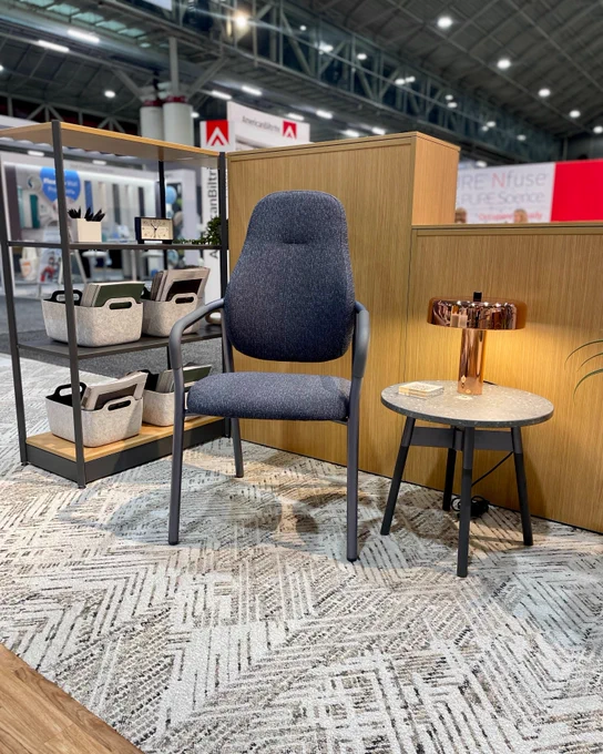A healthcare showroom at Healthcare Design Conference with a dark blue Steelcase Radia chair, side table and small bronze lamp.