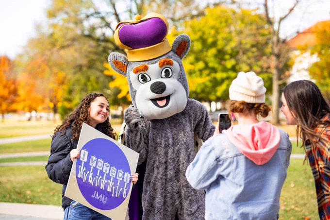 Duke Dog poses for a photo with a student who’s holding an “I Voted” sign.