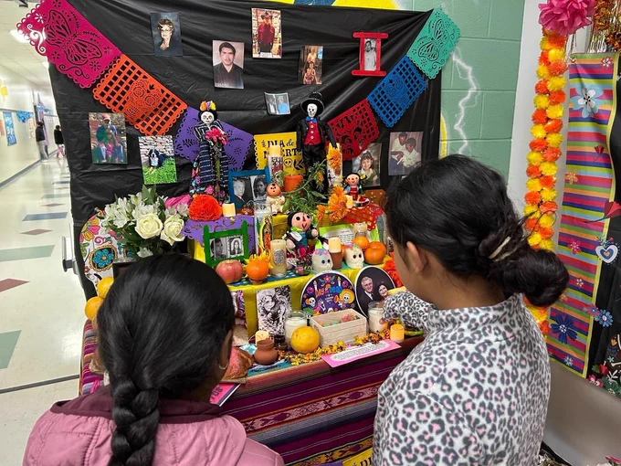Two students looking at the ofrenda's pictures.