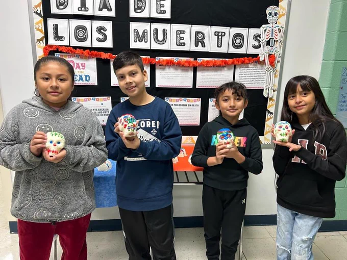 Four students holding sugar skulls for that they made.